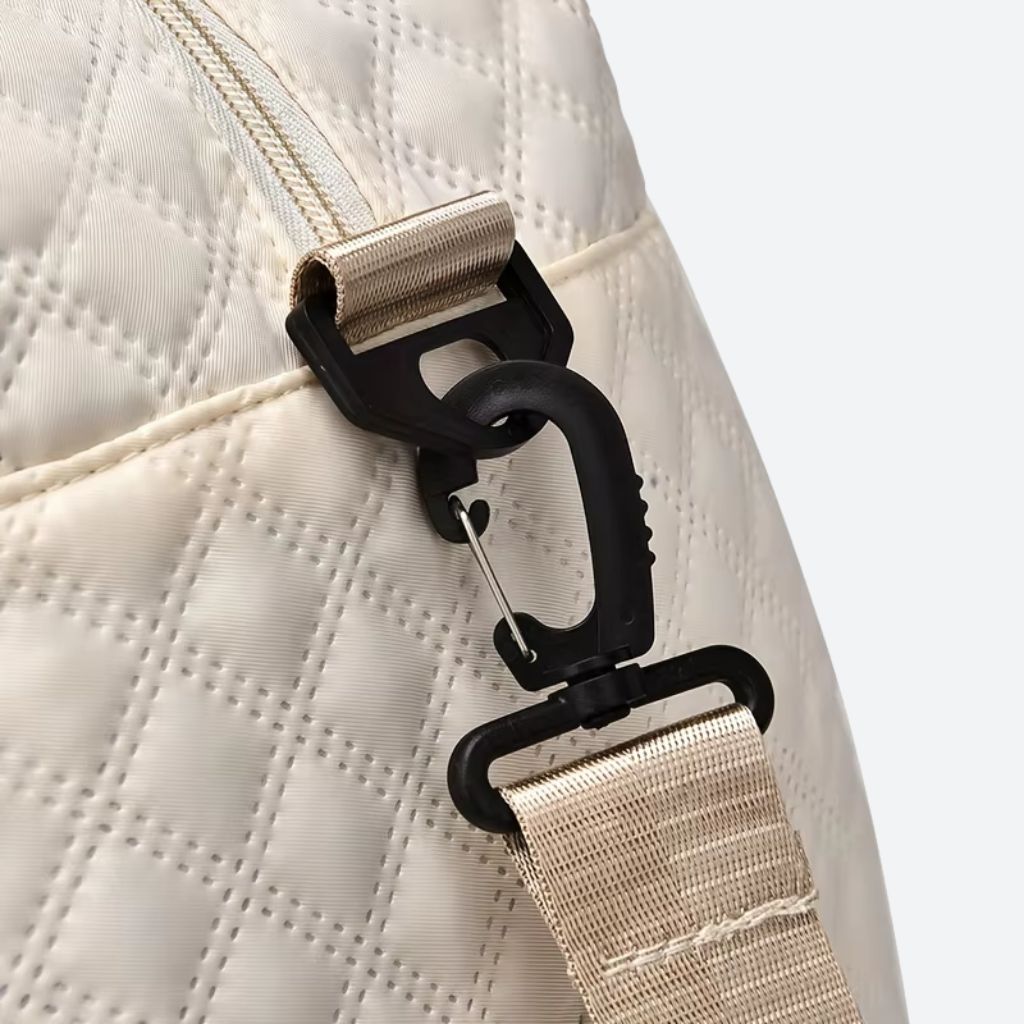 Détail du clip métallique de la bandoulière du sac blanc crème, fixation réglable sur sangle beige