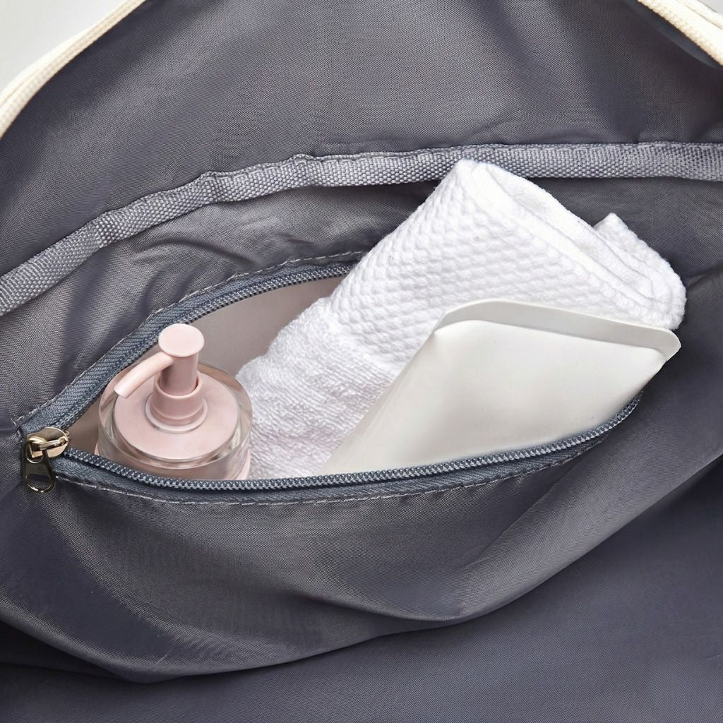 Poche zippée intérieure d'un sac de voyage avec flacon de parfum et serviette blanche pliée, organisée Image