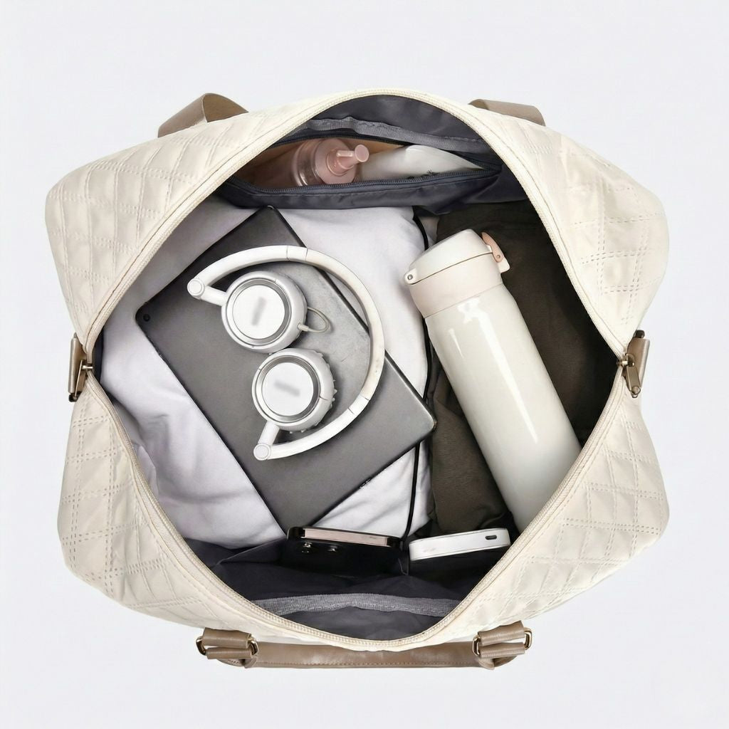 Intérieur du sac blanc crème ouvert avec casque audio, tablette, thermos et vêtements soigneusement rangés