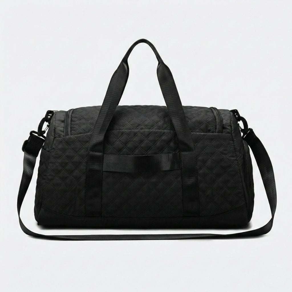 Sac weekend matelassé noir vu de 3/4 : motif diamants très apparent, tirettes triangulaires et bandoulière