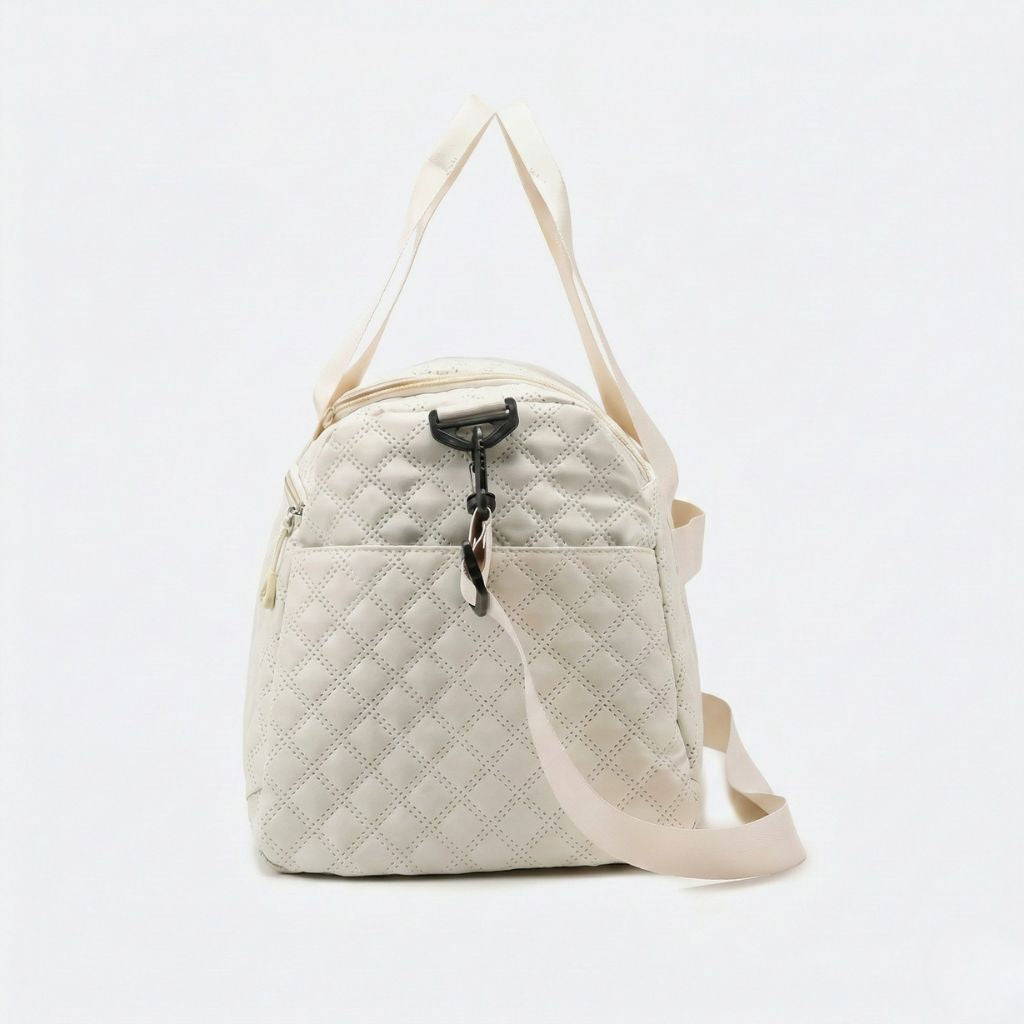 Vue 3/4 du sac weekend matelassé blanc crème avec bandoulière crème étalée et crochet mousqueton noir mat
