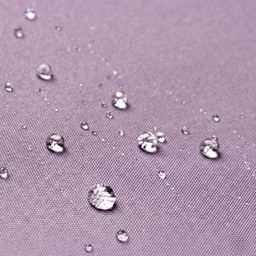 Gros plan du tissu nylon violet du sac de voyage femme, gouttes d'eau en surface démontrant son imperméabilité