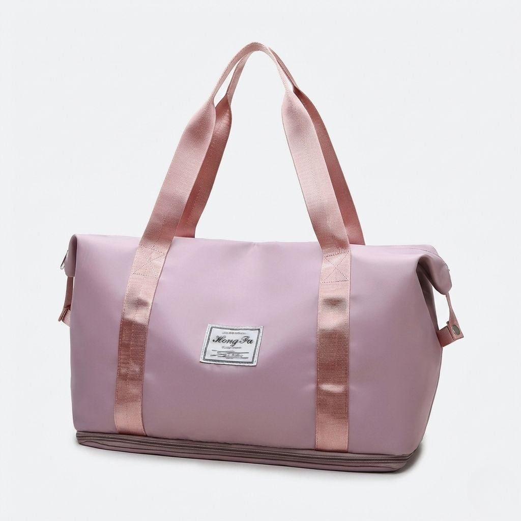 Sac de voyage femme rose poudré extensible, vue 3/4 avant, poignées satinées et étiquette tissée, format cabine