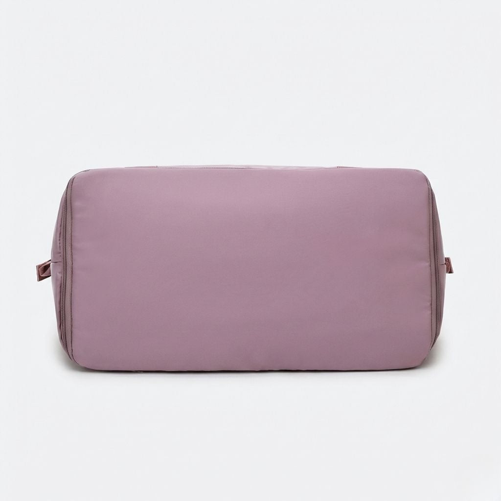 Vue de dessous du sac de voyage femme rose poudré, fond lisse avec fermeture zippée d'extension de volume