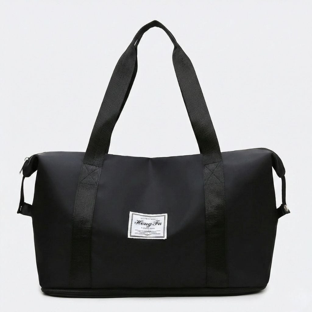 Sac de voyage femme noir extensible, vue de face, poignées et sangles noires assorties, étiquette tissée cabine