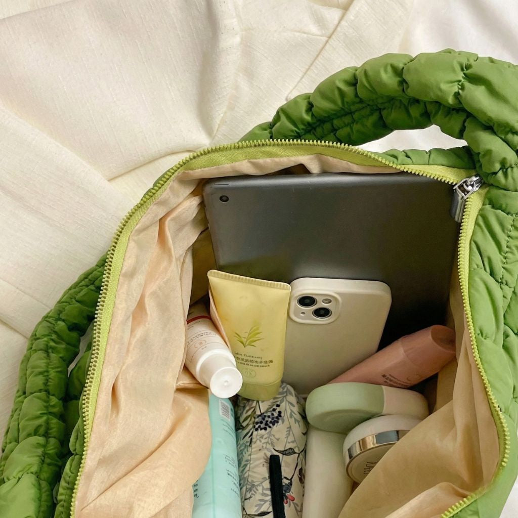 Intérieur ouvert d'un sac de voyage matelassé vert avec tablette, smartphone et produits de beauté bien organisés Image