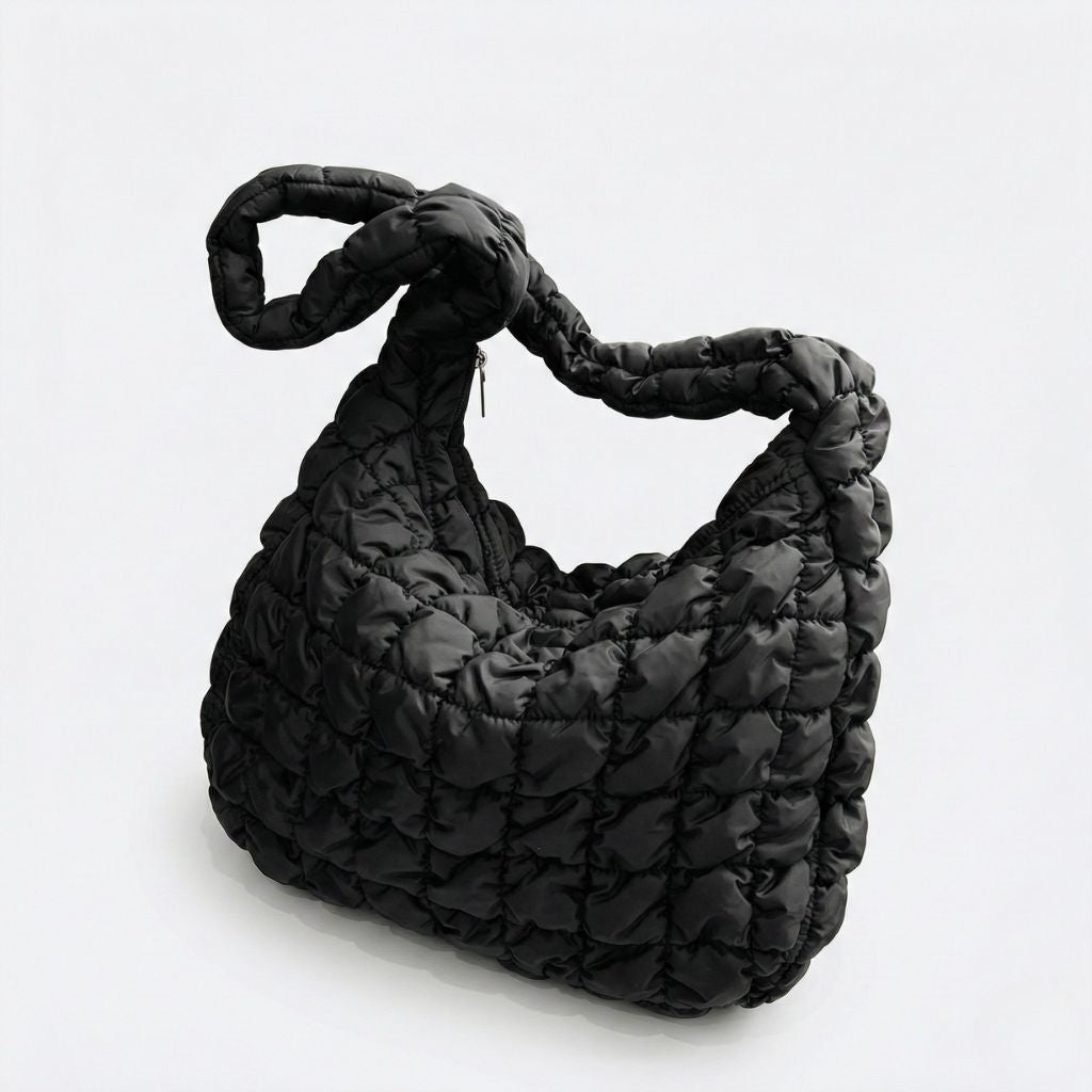 Sac week-end femme matelassé bulle noir avec anse tressée bouffante, coupe hobo, vue de profil sur fond gris