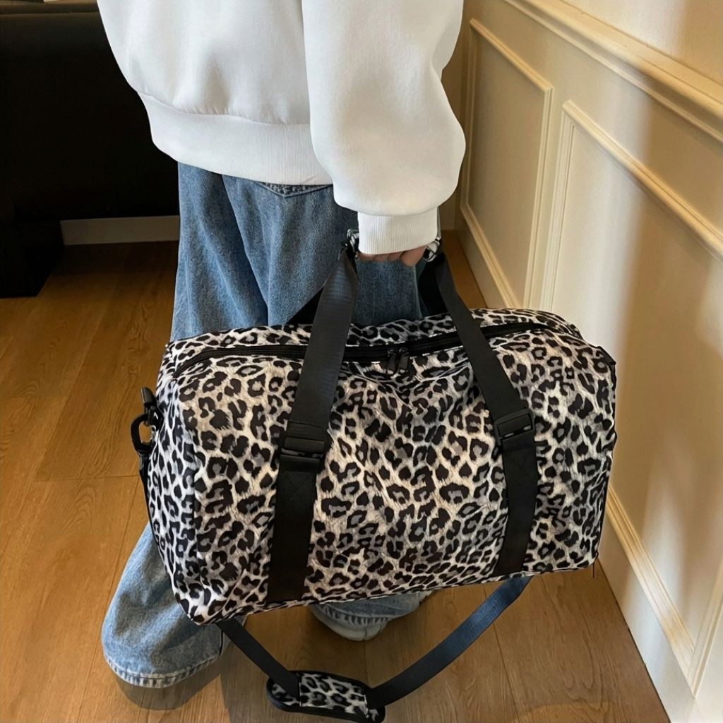 Vue latérale droite du sac polochon à motif léopard beige, détail du mousqueton et de la bandoulière noire