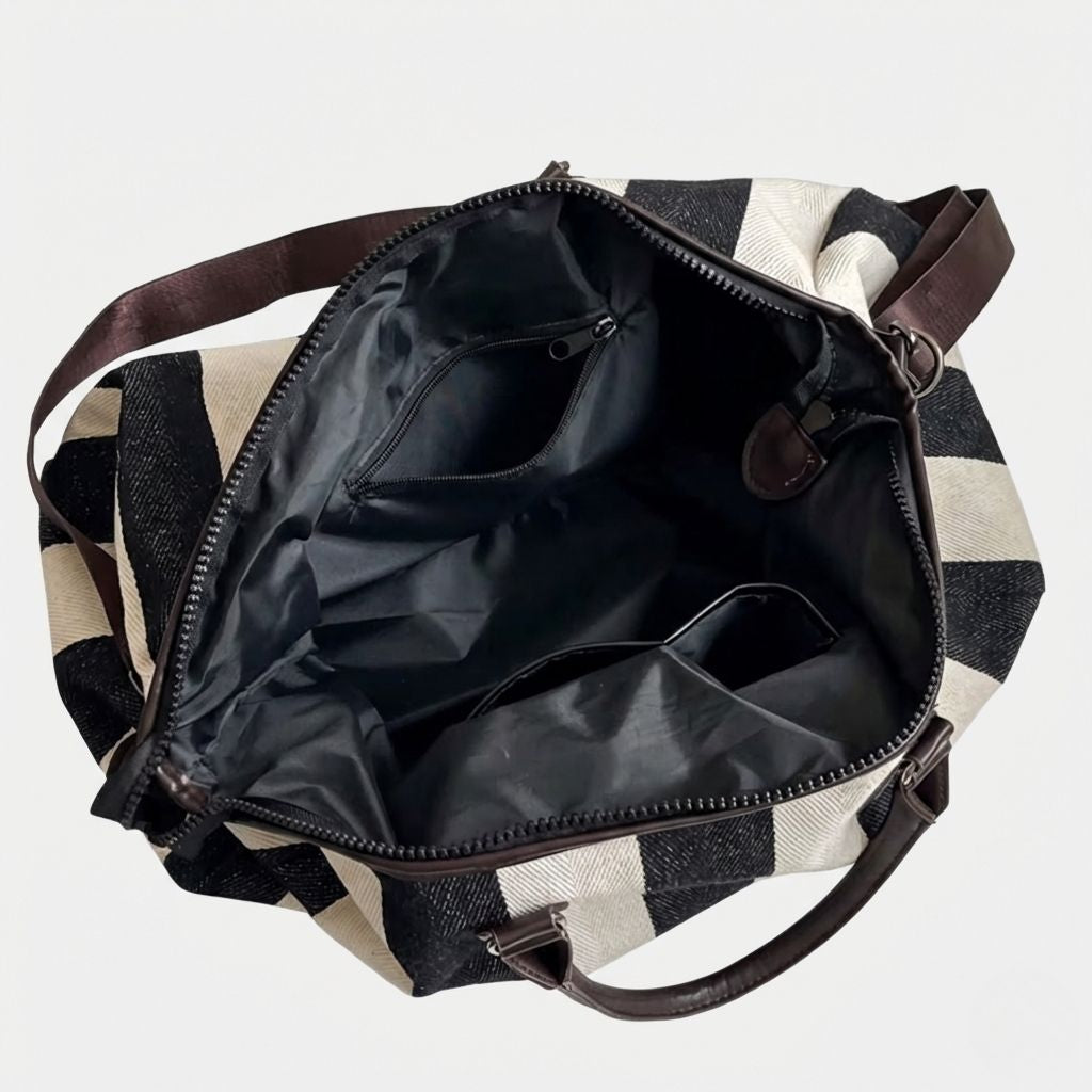 Vue intérieure d'un sac de voyage en toile rayée noir et blanc ouvert, révélant les poches et compartiments Image