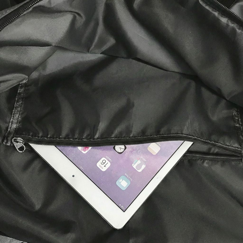 Poche intérieure zippée d'un sac de week-end en nylon noir avec une tablette numérique insérée Image