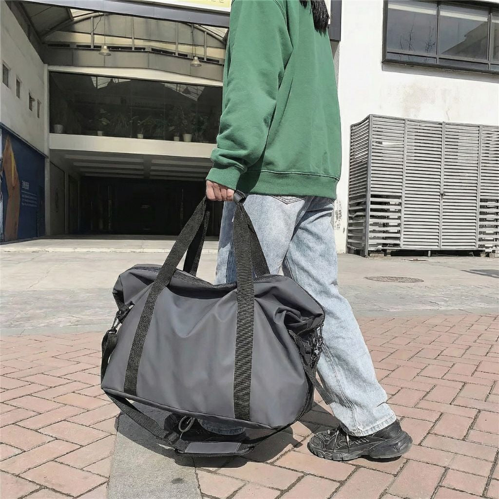 Lifestyle : homme portant le sac de voyage imperméable gris graphite à la main en extérieur urbain citadin