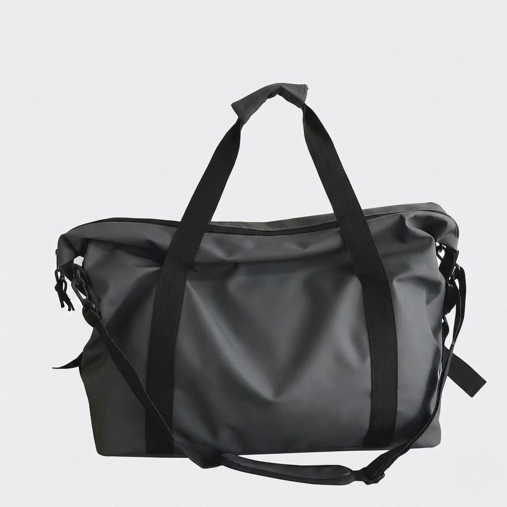 Sac de voyage imperméable noir graphite mat face avant : matière PVC, poignées longues et bandoulière noire