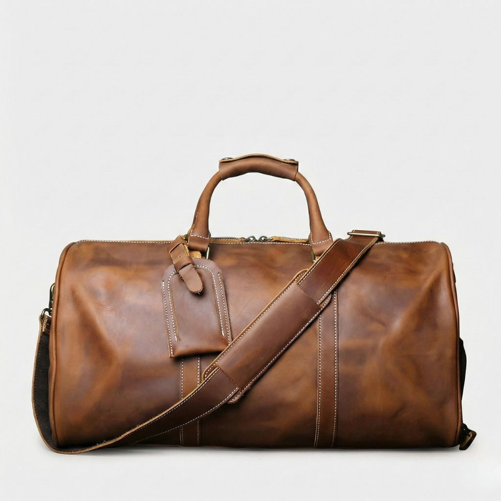 Sac de voyage en cuir véritable marron cognac, coutures blanches, bandoulière réglable et étiquette bagage intégrée