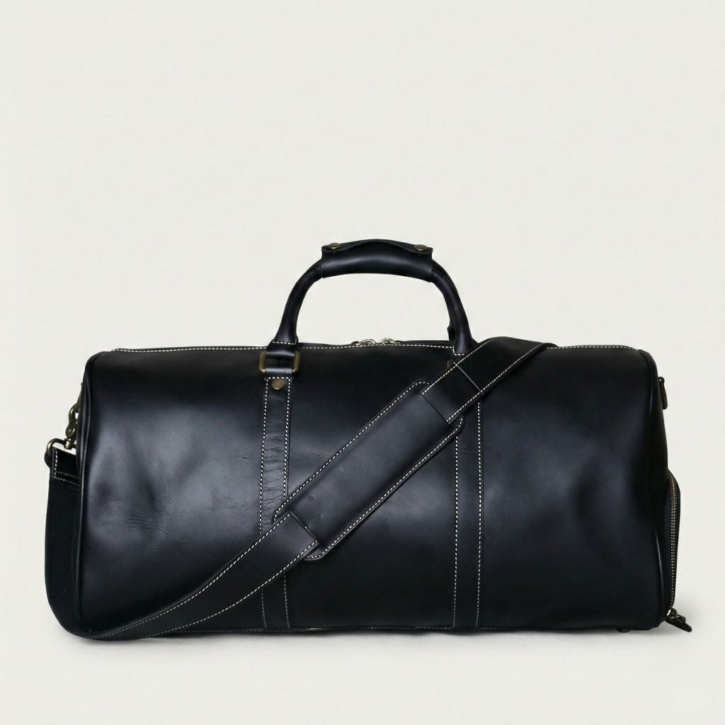 Sac de voyage en cuir noir véritable, bandoulière noire réglable et coutures blanches contrastées sur fond blanc