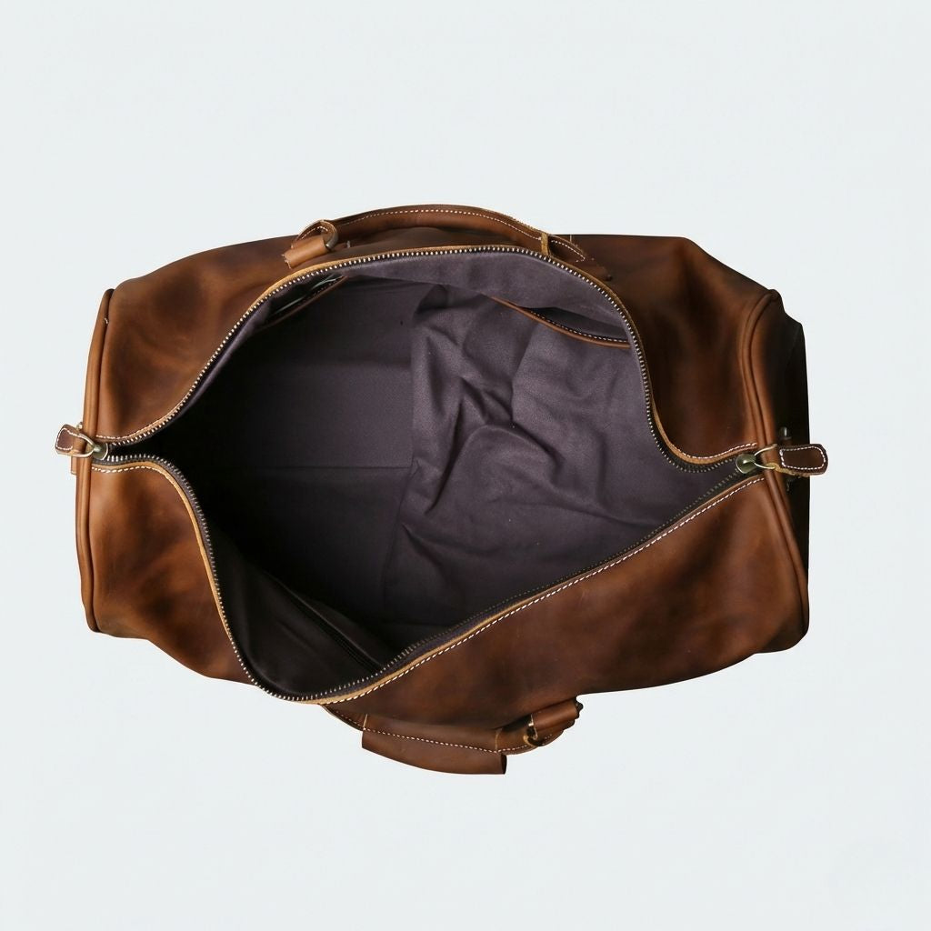 Vue du dessus du sac de voyage en cuir ouvert, révélant un grand compartiment avec doublure intérieure anthracite