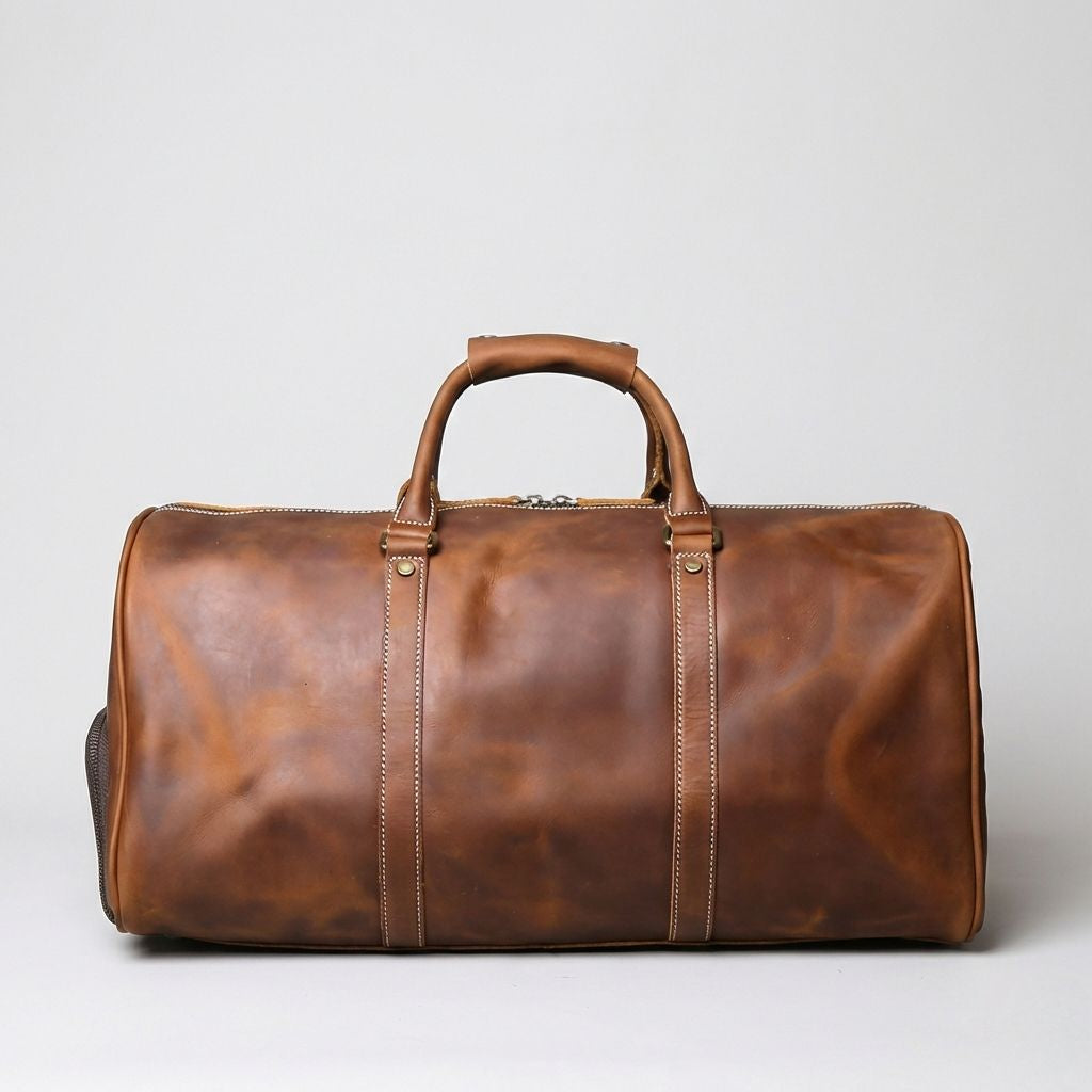 Sac week-end en cuir vintage couleur cognac, coutures blanches apparentes et rivets dorés sur fond blanc