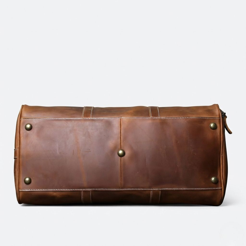 Vue de dessous du sac de voyage en cuir cognac vintage avec quatre pieds de protection en laiton doré Image