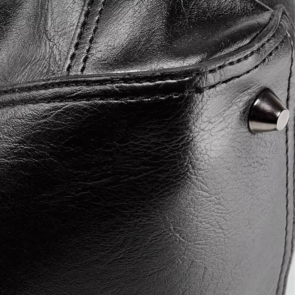 Gros plan du cuir PU noir grainé d'un sac de voyage avec rivet décoratif et coutures contrastantes visibles Image