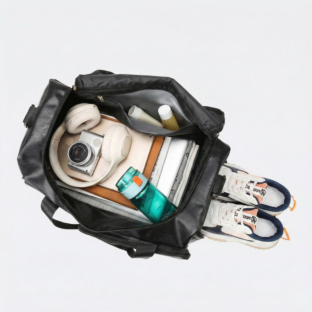 Vue de dessus du sac de voyage en cuir PU noir ouvert, contenant casque, appareil photo, gourde et baskets Image