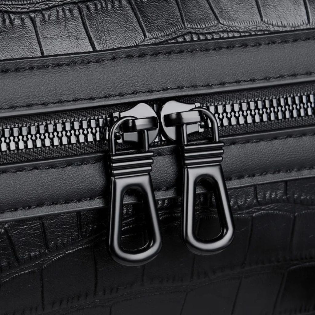 Gros plan sur le double curseur de fermeture éclair noir gunmetal du sac de voyage cabine croco